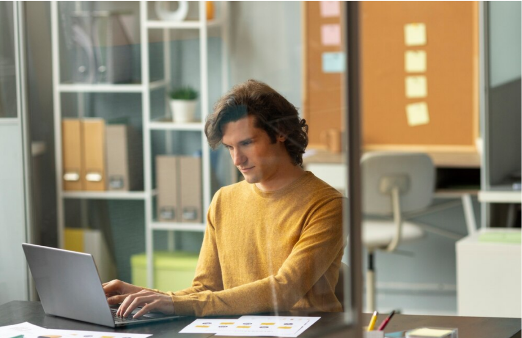 A man working on a laptop in an office.